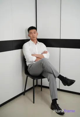 Asian man with short black hair and clean-shaven face, neutral direct gaze seate