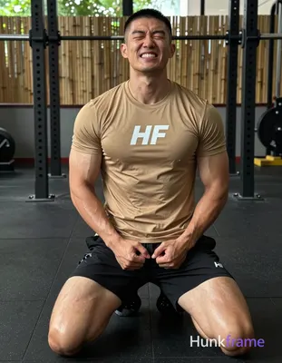 Asian man kneeling on black rubber gym floor, torso upright and slightly arched back with hands clas