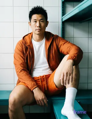 Asian man with short black spiky hair and clean-shaven face, neutral gaze direct eye contact seated 