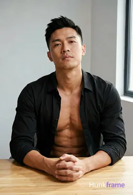 Asian man with short black styled upward hair and clean-shaven face, seated at a