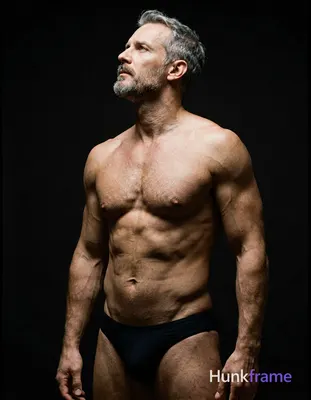 A handsome white man in his forties with short graying hair and a goatee stands 
