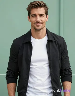 A handsome masculine man standing straight with a slight smile, wearing a black 