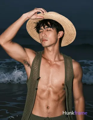 Asian man with tanned skin and short black straight hair stands in shallow water at night, adjusting
