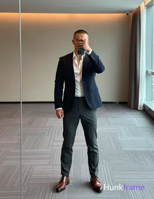 Adult man with medium-brown skin and buzz cut stands facing a large mirror in a 