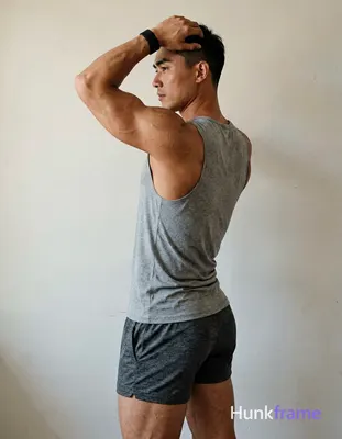 A handsome masculine man as a Xiaohongshu fitness influencer, standing in profile with left arm rais
