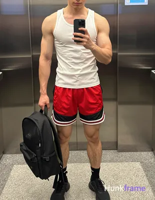 A handsome Asian man standing with his torso slightly leaned forward, holding a 