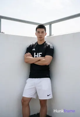 Asian man with short black buzz cut and clean-shaven face, standing leaning agai