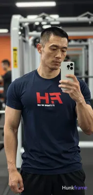 Asian man with medium-tan skin and short buzz cut, light stubble on jawline holding white smartphone