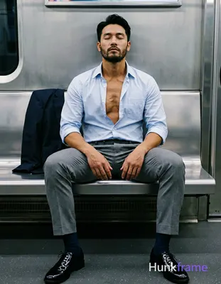 An Asian man with light-medium skin and short black hair styled back sits on a subway bench, eyes cl