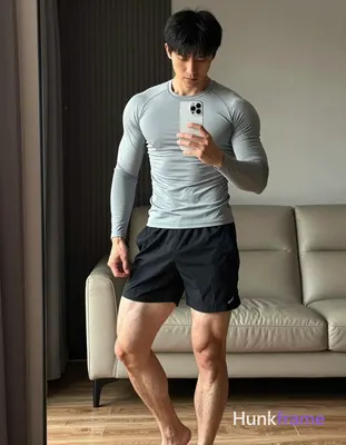 Full-body vertical mirror selfie of an adult Asian man with short black hair and straight bangs, cle
