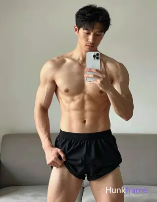Asian adult man with light to medium tan skin and short straight black hair stands before a mirror i