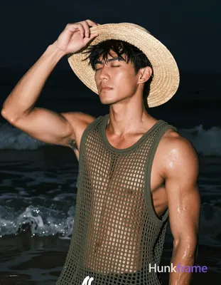 Asian man with tanned skin and short black straight hair stands in shallow water at night, adjusting