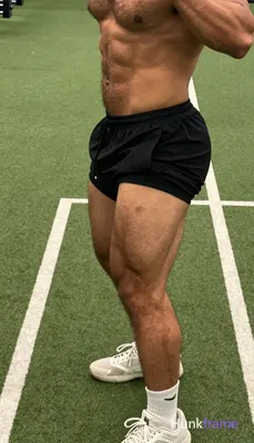 High-angle muscle bear close-up on lower body of shirtless man with thick thighs and defined quadric