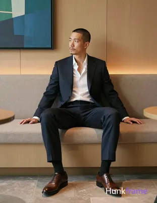 an anonymous figure man with short buzz cut and light stubble sits contemplatively in a modern loung