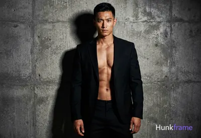 A handsome Asian man with a compact athletic build and well-defined abs, wearing only a black suit j