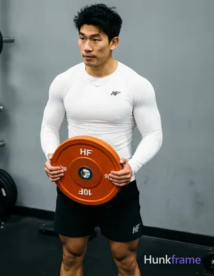 Asian man with light-medium skin and short black textured hair stands in a gym, holding an orange 10