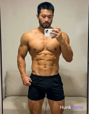 Asian adult man with light to medium tan skin and short straight black hair stands before a mirror i