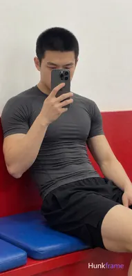 Seated sideways on red bench with blue cushion, wearing dark grey tight-fitting short-sleeve compres