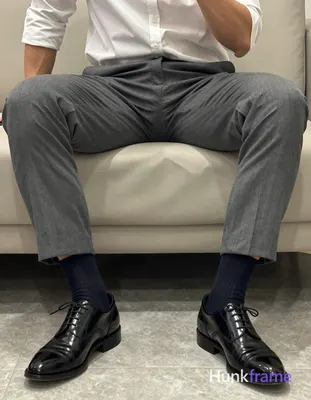 Photoreal photograph of a seated man in a torso-only crop. He is wearing gray su