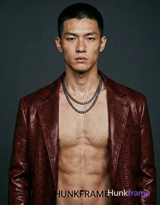 A fair-skinned white man with freckles and short dark cropped hair stands shirtless in a head-and-sh
