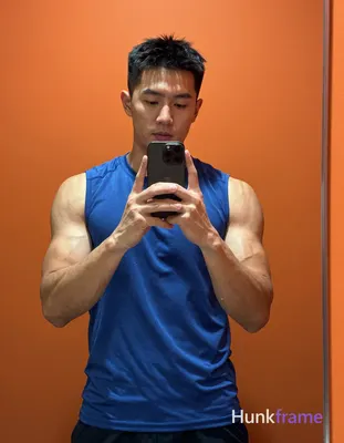 Asian man with short black hair and clean-shaven face, standing facing a bathroo
