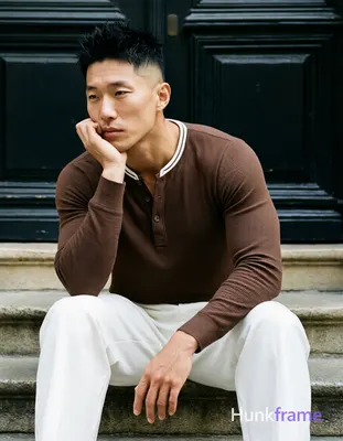 Asian man with short black textured spiky hair fading to tight buzz, clean-shaven face, neutral cont