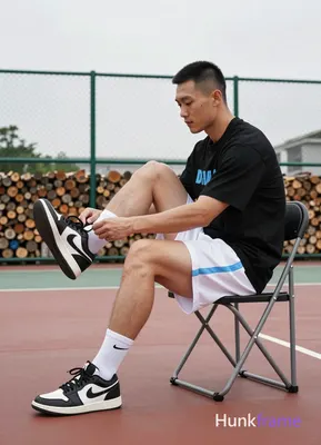 Asian man with short black buzz cut and clean-shaven face, seated in profile on a folding chair at a