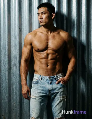 A handsome adult man with medium-tan skin and short dark hair stands leaning aga