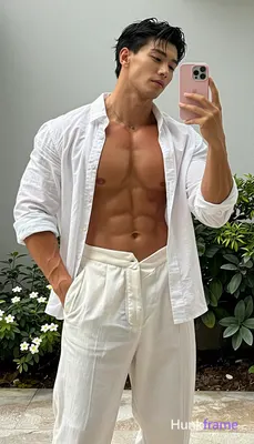 Asian man medium-dark tan skin taking a vertical mirror selfie, standing upright with torso angled l