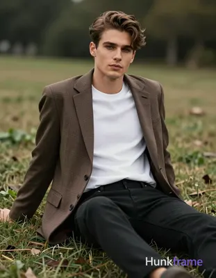 A handsome Caucasian man with fair skin and brown hair styled upward sits on a g