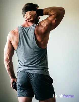 Striking full-bleed vertical wallpaper composition of a muscular adult man stand