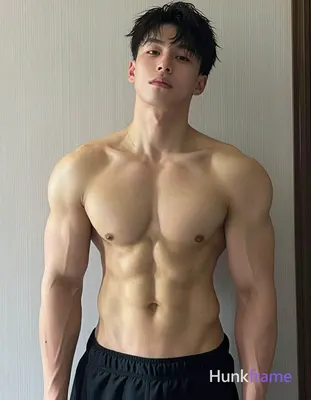 He stands shirtless, torso slightly angled right, displaying defined pectoral muscles and visible ab