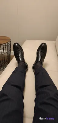 Adult man seated with legs extended forward, feet resting on a light-colored sur