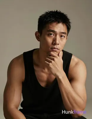 Asian man with medium-tan skin and short textured black hair, seated in a thinking pose with right h
