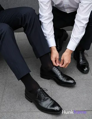 Two adult men in a tight close-up fashion editorial shot focusing on lower legs and hands against la