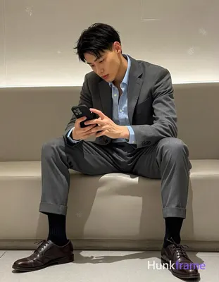 Asian man with short black textured hair and clean-shaven face, seated sideways 