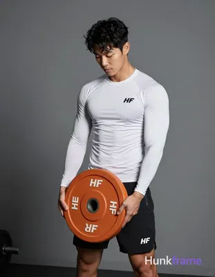 Asian man with light-medium skin and short black textured hair stands in a gym, holding an orange 10