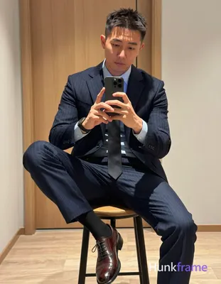 Asian man with light to medium tan skin and short textured dark hair, clean-shaven face holding a sm