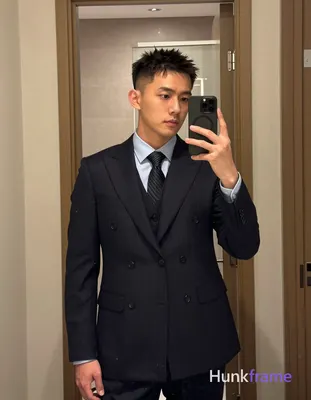 Asian man with short textured dark crop hair and clean-shaven face stands uprigh