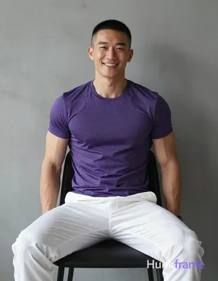 Asian man with short buzz cut and clean-shaven face smiling, seated upright on a