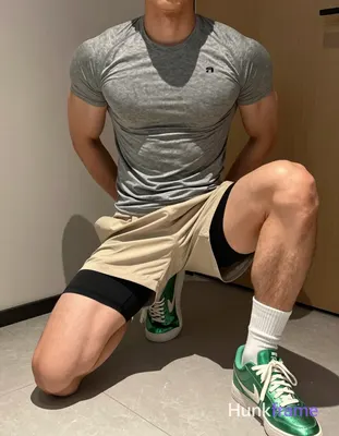 Adult muscular man kneeling on light-colored tiled floor, torso leaning forward slightly with hands 