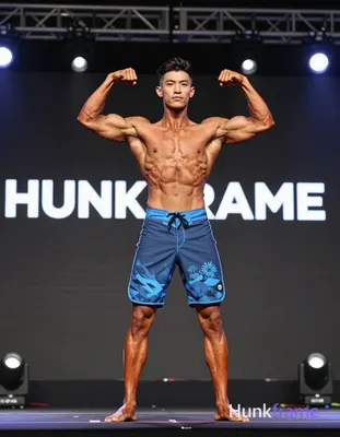 A handsome adult man with tanned skin and short dark hair with fade stands cente