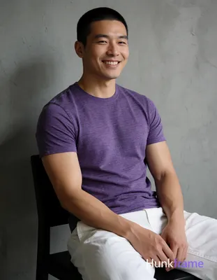 Asian man with short buzz cut and clean-shaven face smiling, seated upright on a