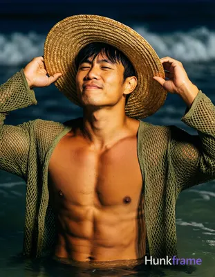Asian man with tanned skin and short black straight hair stands in shallow water at night, adjusting