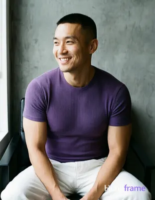 Asian man with short buzz cut and clean-shaven face smiling, seated upright on a