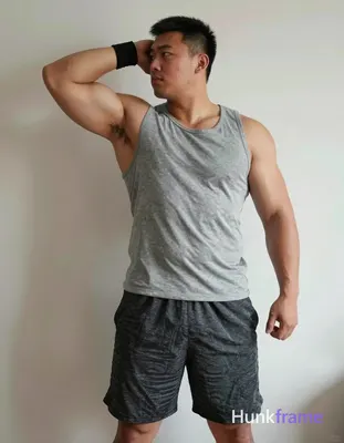 A big hairy stocky masculine man with bear energy, standing in profile with left arm raised behind h