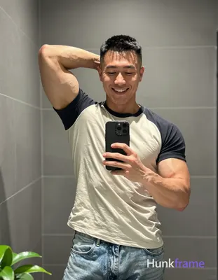 Asian man with short black buzz cut and high fade stands in front of a bathroom 