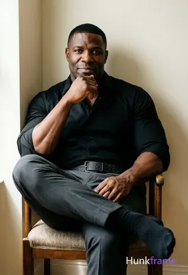 A rugged adult man with short black hair and clean-shaven face sits centered in 