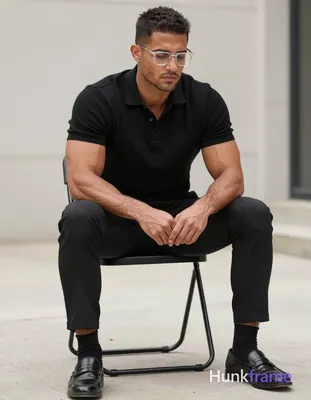 A rugged medium-dark skinned man with short textured dark hair and clear-framed 