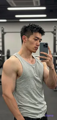 Asian man with short spiky black hair and high forehead stands in profile facing right, holding dark